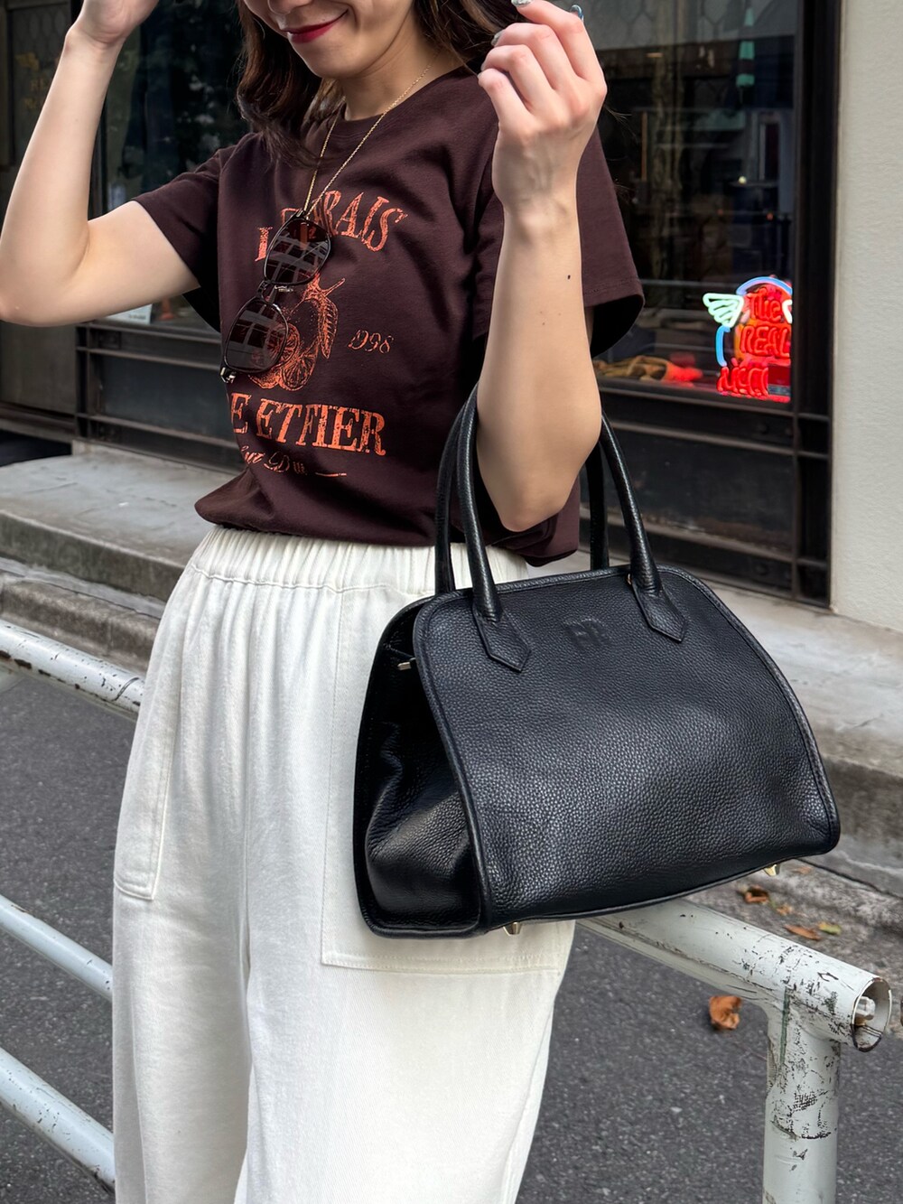 ブラウン系のTシャツ/カットソー、ホワイト系のデニムパンツ、ブラック系のショルダーバッグを着用したレディースの夏コーディネートの3枚目の写真
