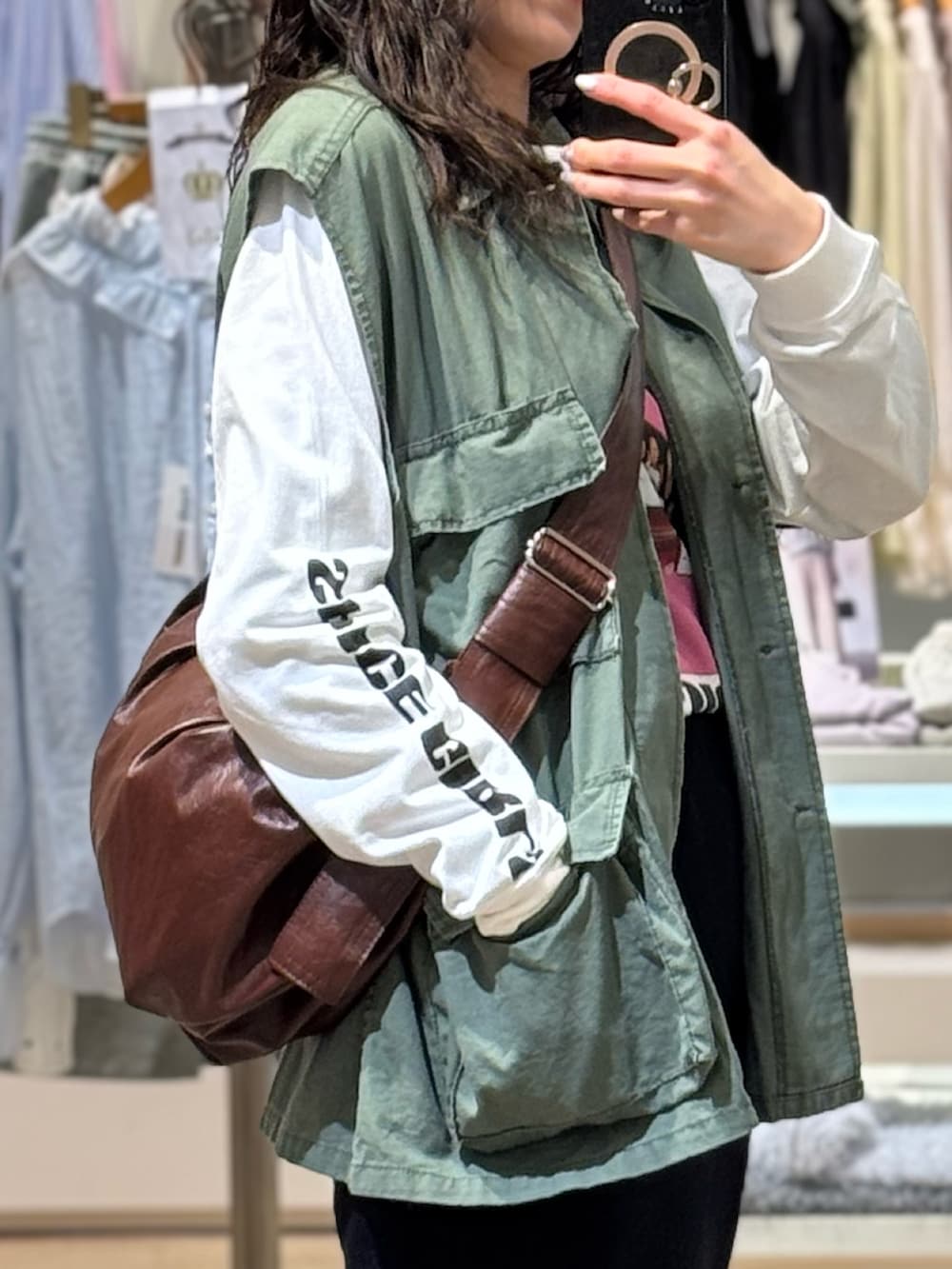 グリーン系のミリタリージャケット、ホワイト系のTシャツ/カットソー、ブラウン系のショルダーバッグを着用したレディースの春コーディネートの3枚目の写真