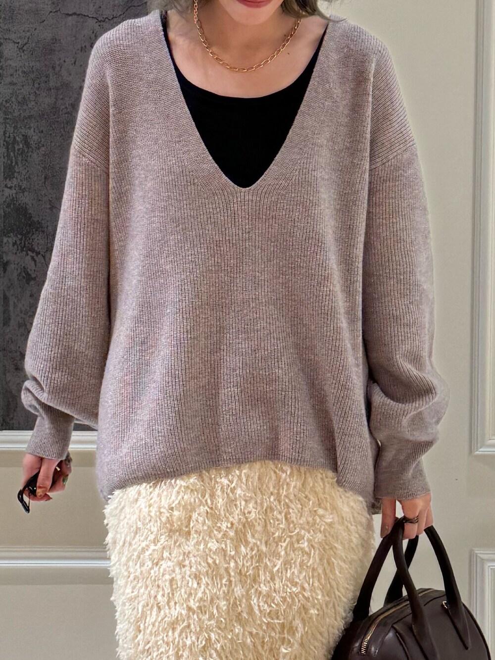 ブラウン系のボストンバッグ、ベージュ系のニット/セーター、ホワイト系のスカートを着用したレディースの秋コーディネートの2枚目の写真