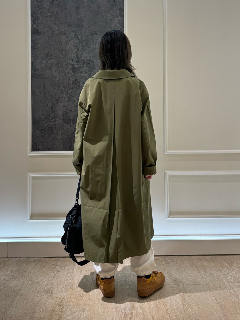 グリーン系のステンカラーコート、グレー系のTシャツ/カットソー、ホワイト系のカーゴパンツを着用したレディースの冬コーディネートの2枚目の写真