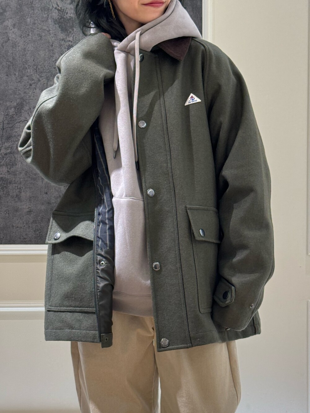 グリーン系のブルゾン、ベージュ系のパーカー、ホワイト系のその他パンツを着用したレディースの冬コーディネートの2枚目の写真