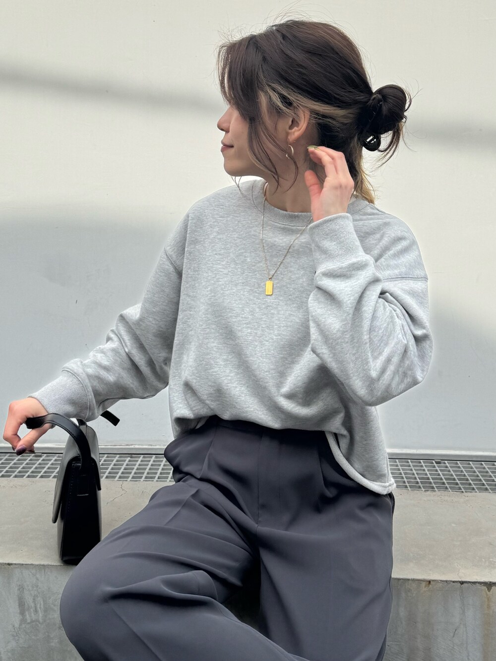 グレー系のスウェット、グレー系のスラックス、ブラック系のショルダーバッグを着用したレディースの春コーディネートの4枚目の写真