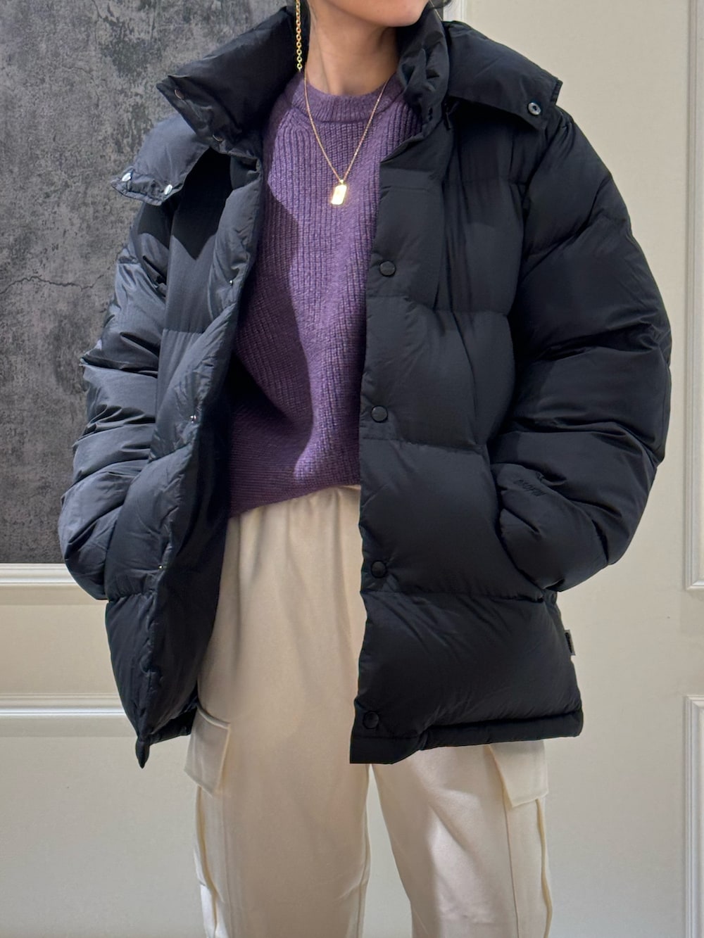 ブラック系のダウンジャケット/コート、パープル系のニット/セーター、ホワイト系のカーゴパンツを着用したレディースの冬コーディネートの2枚目の写真