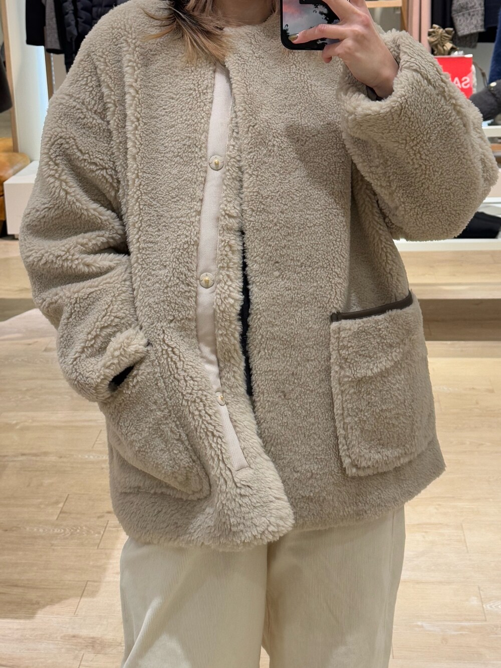 ブラウン系のノーカラーコート、ホワイト系のその他パンツ、グリーン系のニットキャップ/ビーニーを着用したレディースの冬コーディネートの3枚目の写真