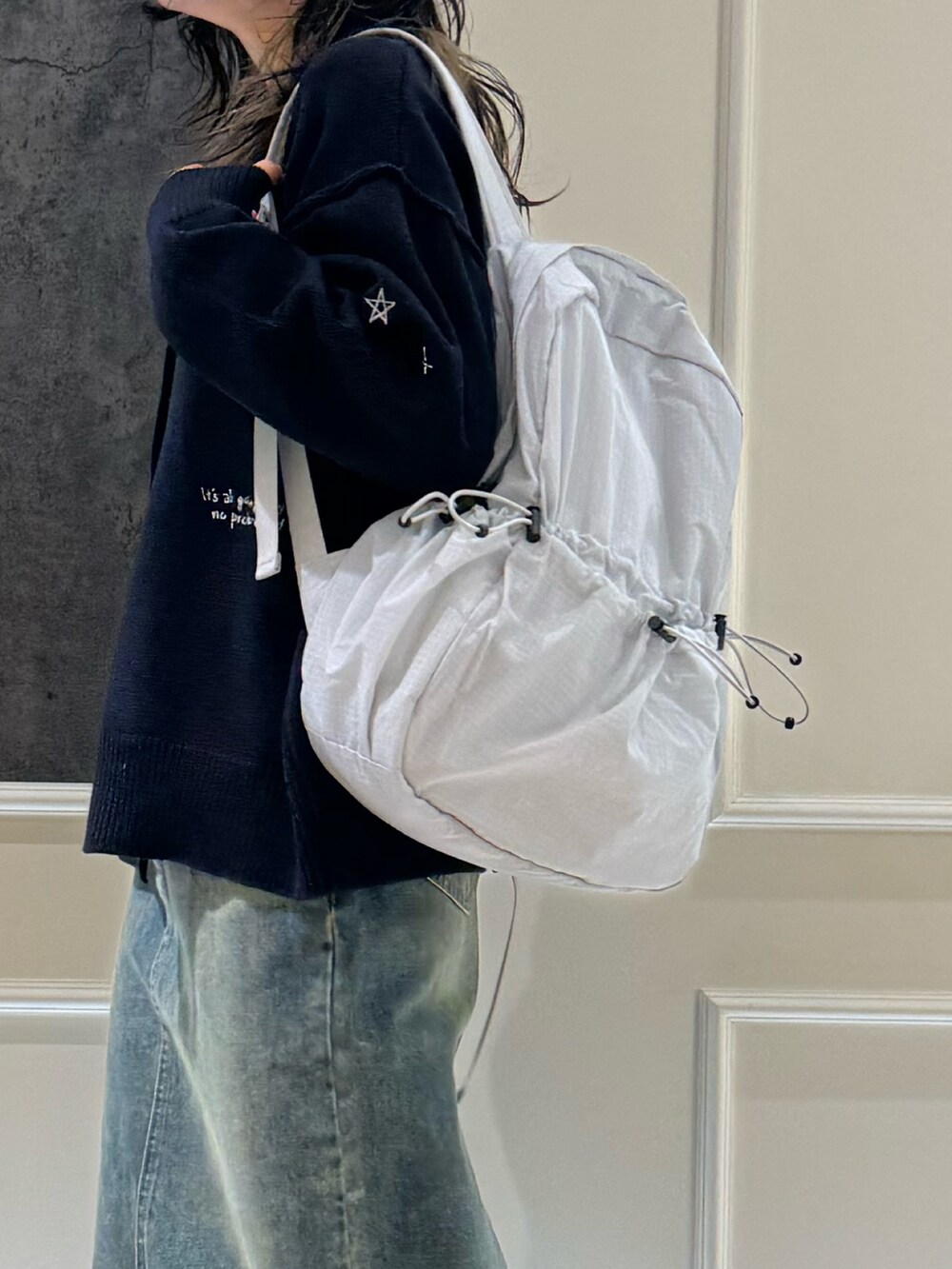 ホワイト系のカーディガン/ボレロ、ブルー系のデニムスカート、ブラック系のバックパック/リュックを着用したレディースの冬コーディネートの3枚目の写真