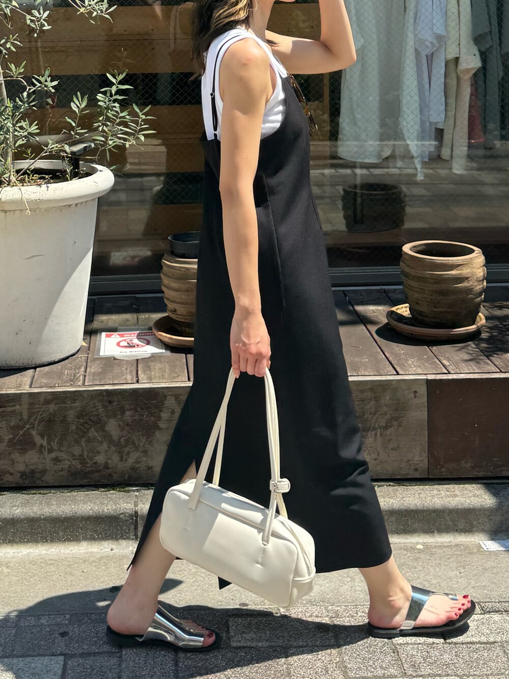 ブラック系のワンピース、ホワイト系のボストンバッグ、シルバー系のサンダルを着用したレディースの夏コーディネートの3枚目の写真