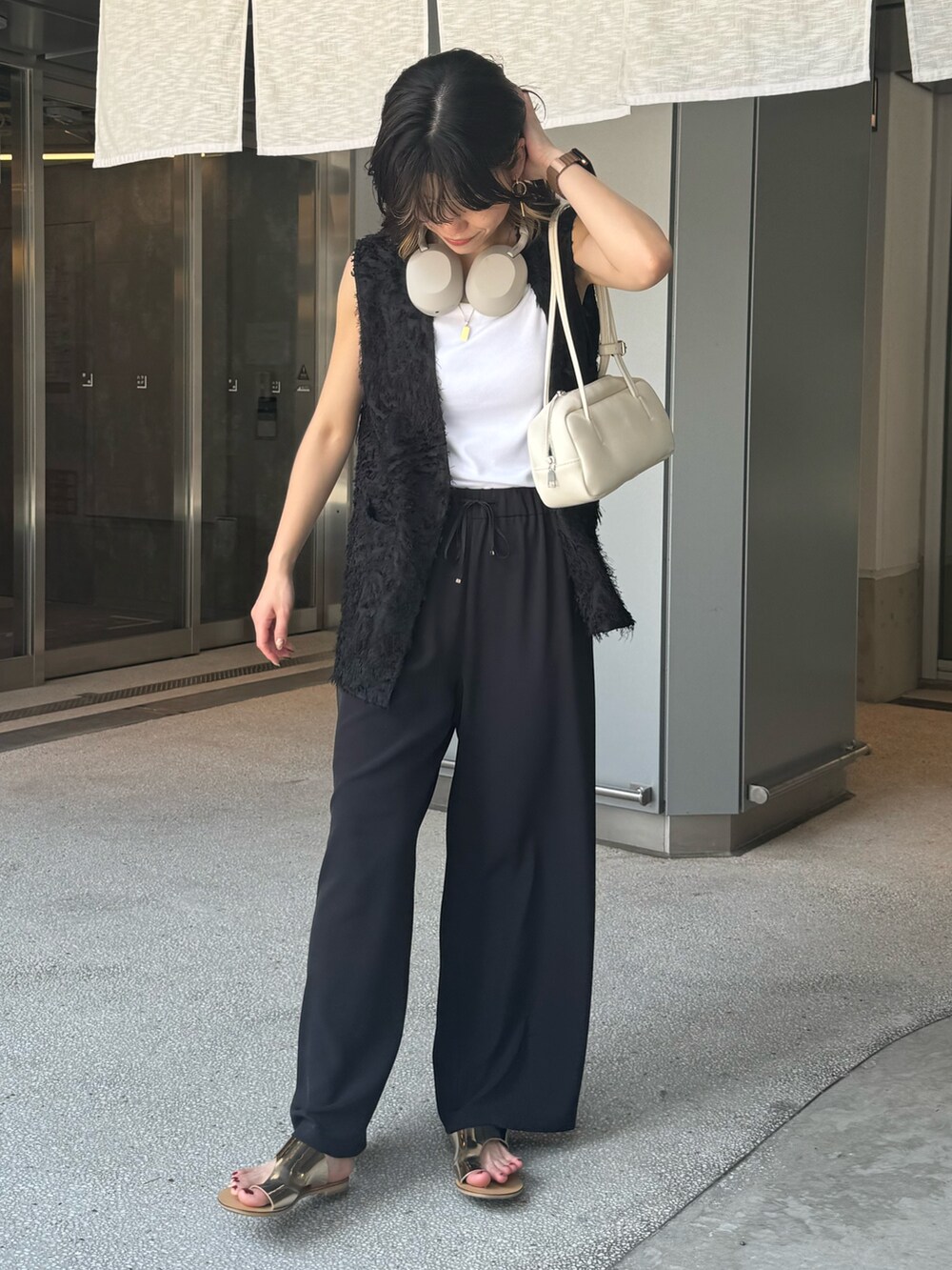 ブラック系のベスト、グレー系のその他パンツ、シルバー系のサンダルを着用したレディースの夏コーディネートの2枚目の写真