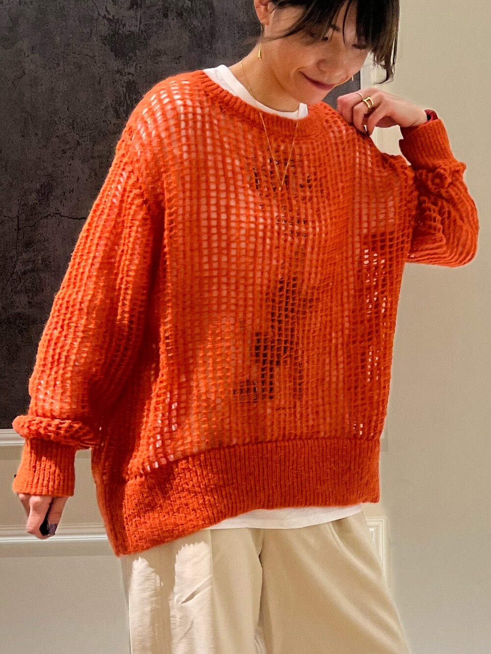 オレンジ系のニット/セーター、ブラック系のその他パンツ、ブラック系のスニーカーを着用したレディースの秋コーディネートの2枚目の写真