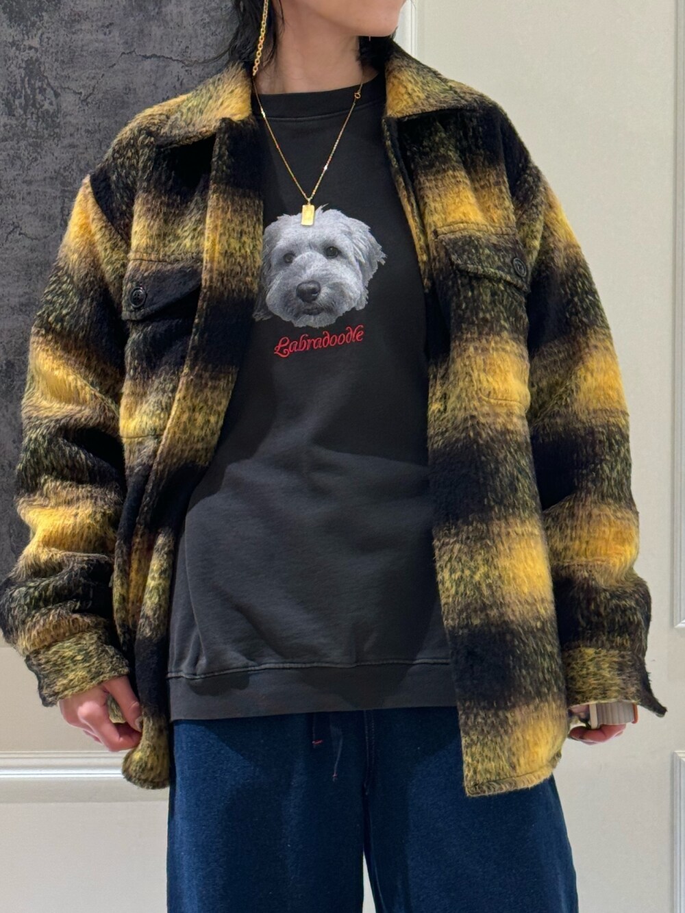 イエロー系のブルゾン、ブラック系のスウェット、ブルー系のデニムパンツを着用したレディースの冬コーディネートの2枚目の写真