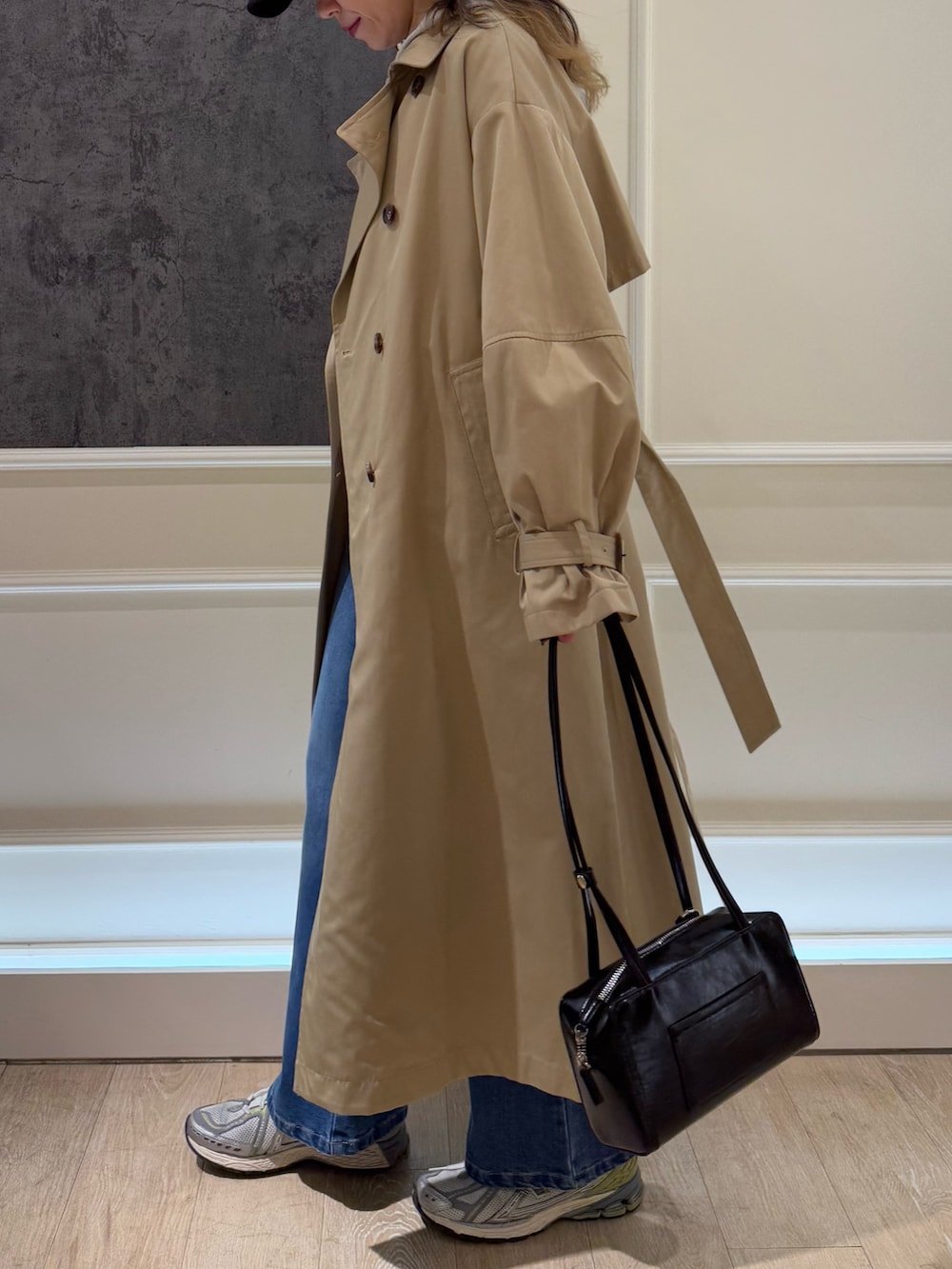 グレー系のニット/セーター、ベージュ系のトレンチコート、ブルー系のデニムパンツを着用したレディースの冬コーディネートの2枚目の写真