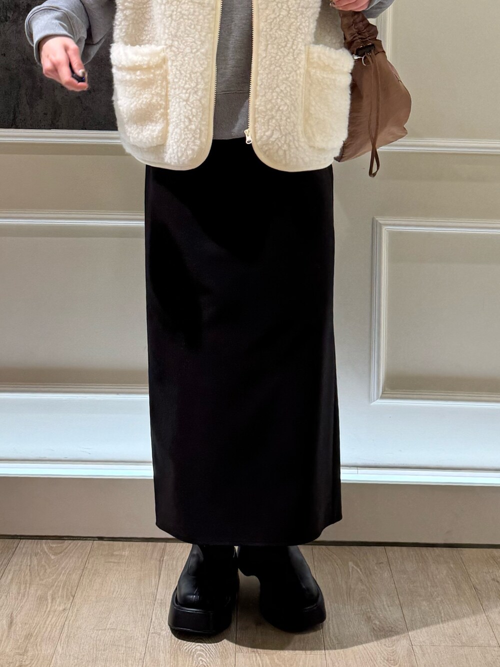 グレー系のスウェット、ブラック系のスカート、ブラック系のブーツを着用したレディースの冬コーディネートの3枚目の写真