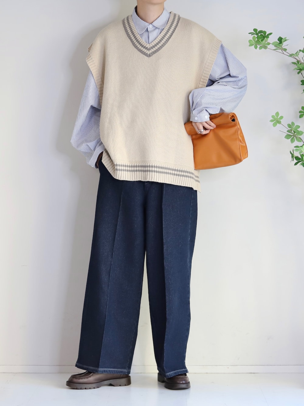 ベージュ系のベスト、ブルー系のスラックス、イエロー系のハンドバッグを着用したメンズの秋コーディネートの2枚目の写真