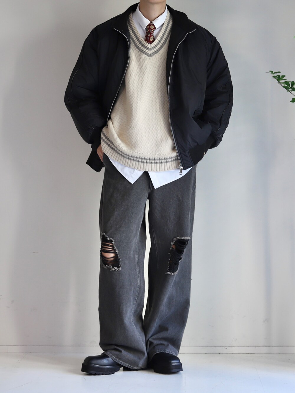 ベージュ系のベスト、ブラック系のデニムパンツ、ブラック系のブーツを着用したメンズの秋コーディネートの2枚目の写真