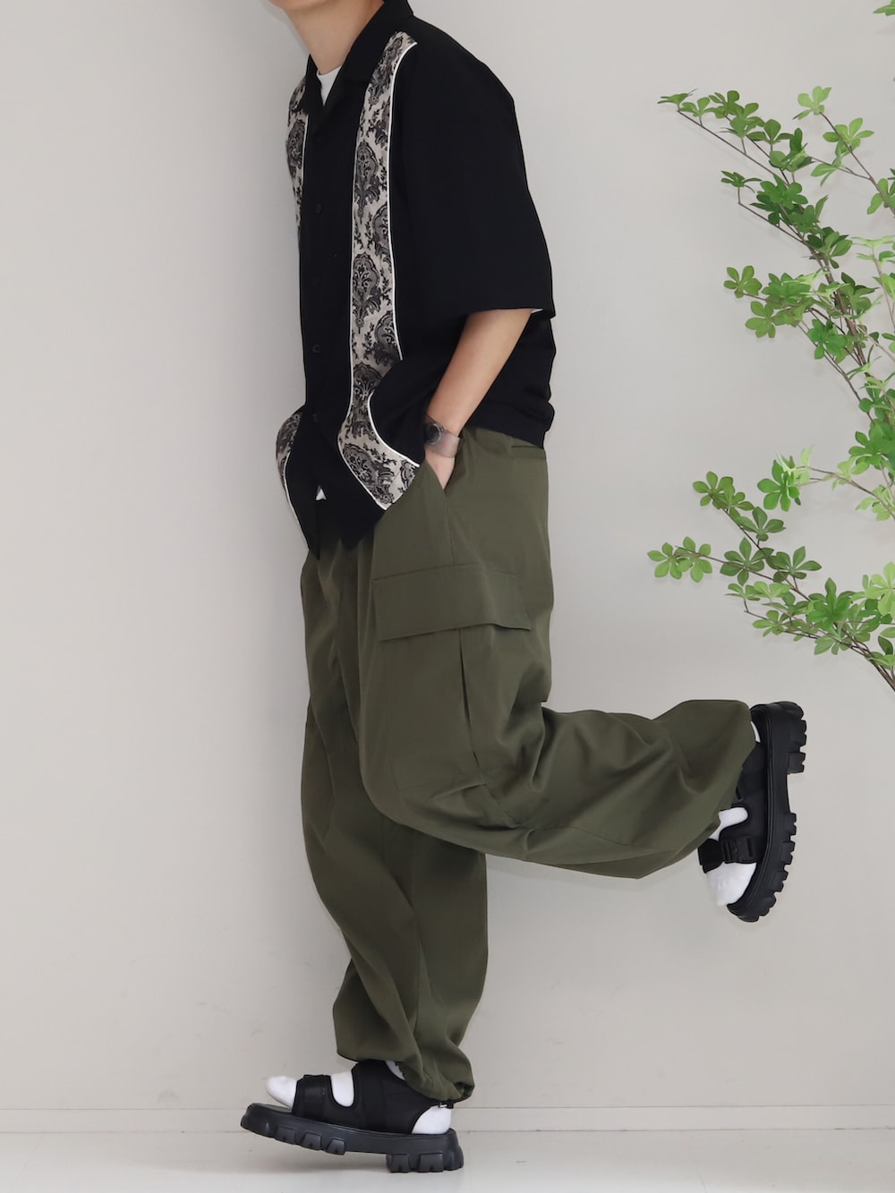 ブラック系のシャツ/ブラウス、グリーン系のカーゴパンツ、ブラック系のサンダルを着用したメンズの夏コーディネートの2枚目の写真