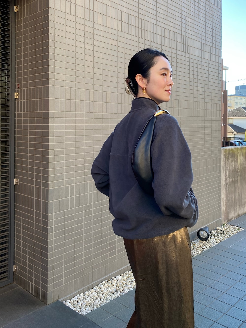 ゴールド系のスカート、ブラック系のハンドバッグ、グレー系のその他トップスを着用したレディースの冬コーディネートの2枚目の写真