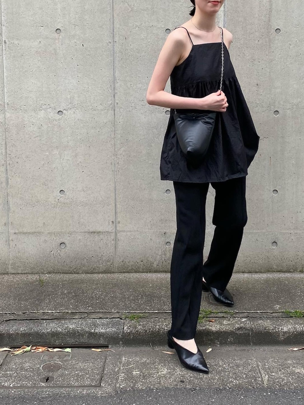 ブラック系のトートバッグ、ブラック系のパンツ、ブラック系のキャミソールを着用したレディースの春コーディネートの2枚目の写真