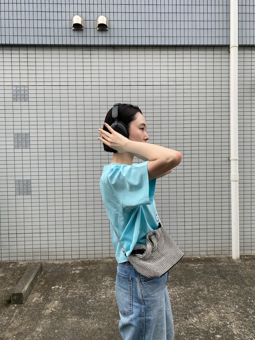 ホワイト系のスニーカー、グレー系のデニムパンツ、シルバー系のバッグを着用したレディースの春コーディネートの2枚目の写真