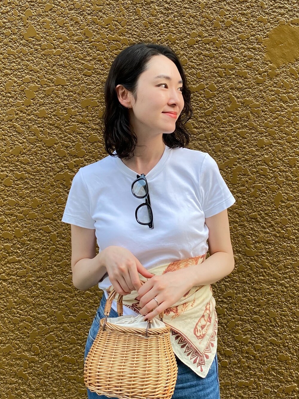 ベージュ系のかごバッグ、ブルー系のデニムパンツ、レッド系のパンプスを着用したレディースの夏コーディネートの3枚目の写真