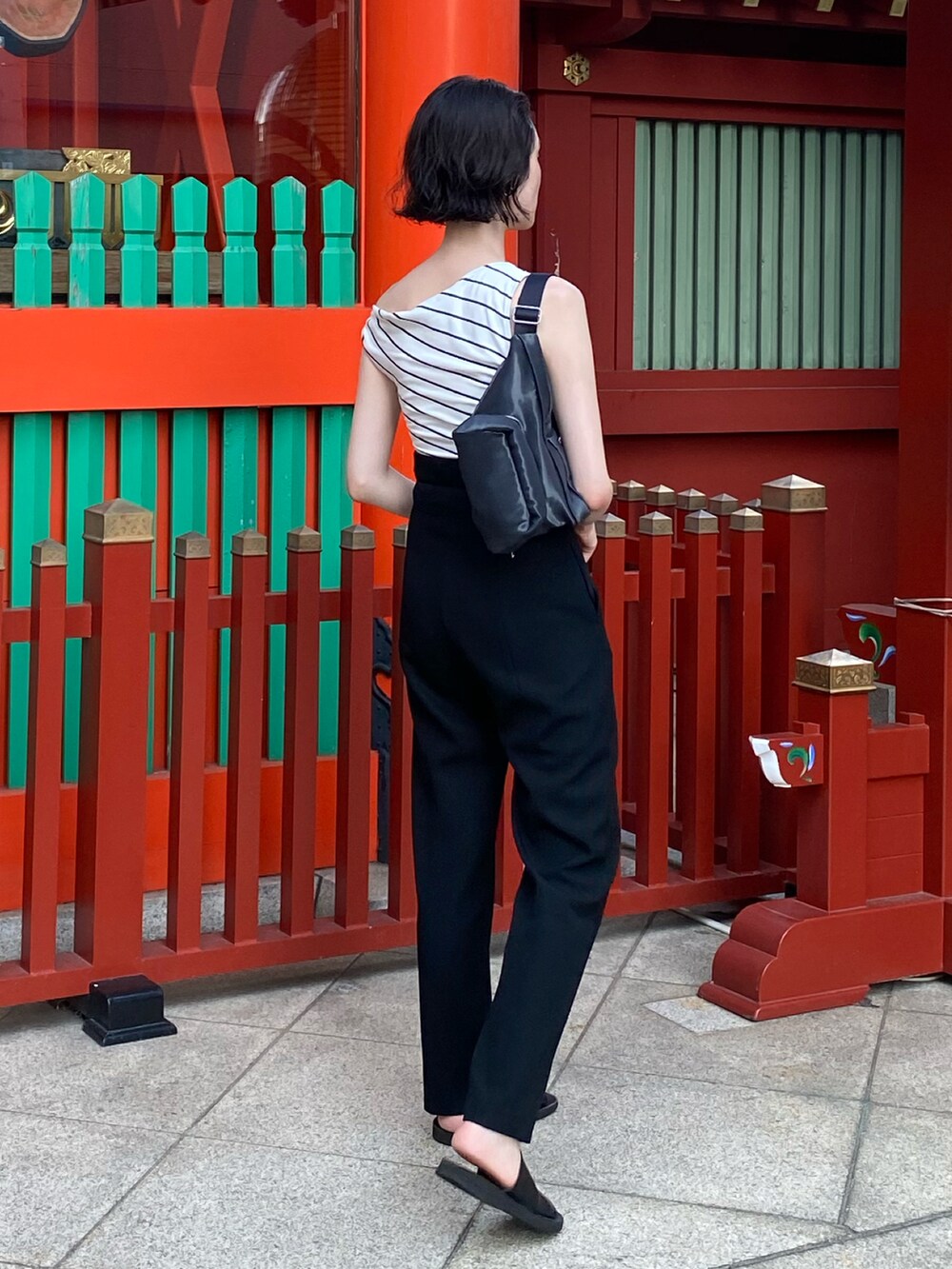 ブルー系のバッグ、ブラック系のパンツ、ブラック系のサンダルを着用したレディースの秋コーディネートの2枚目の写真