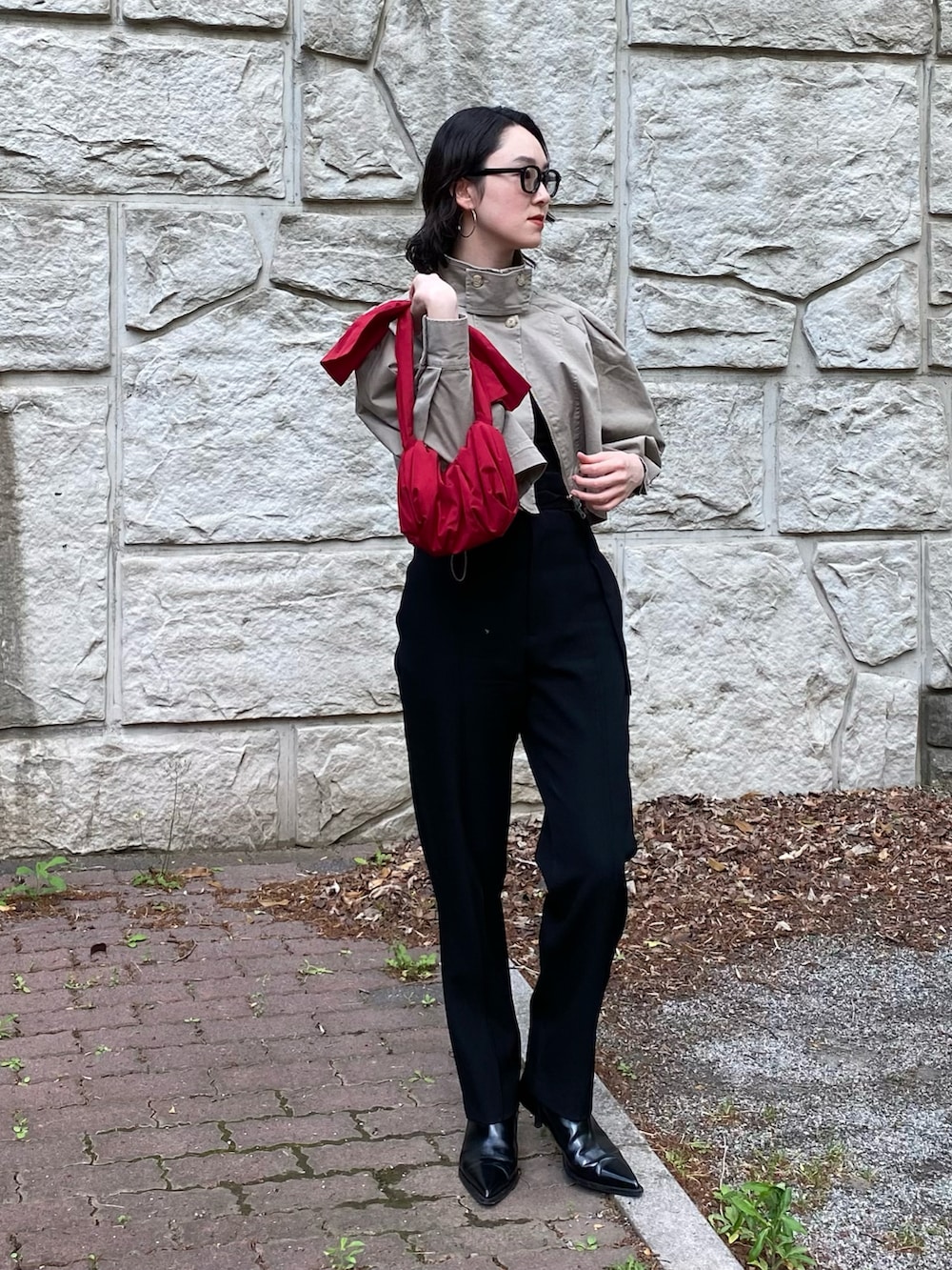 レッド系のハンドバッグ、ベージュ系のミリタリージャケット、ブラック系のパンツを着用したレディースの春コーディネートの2枚目の写真