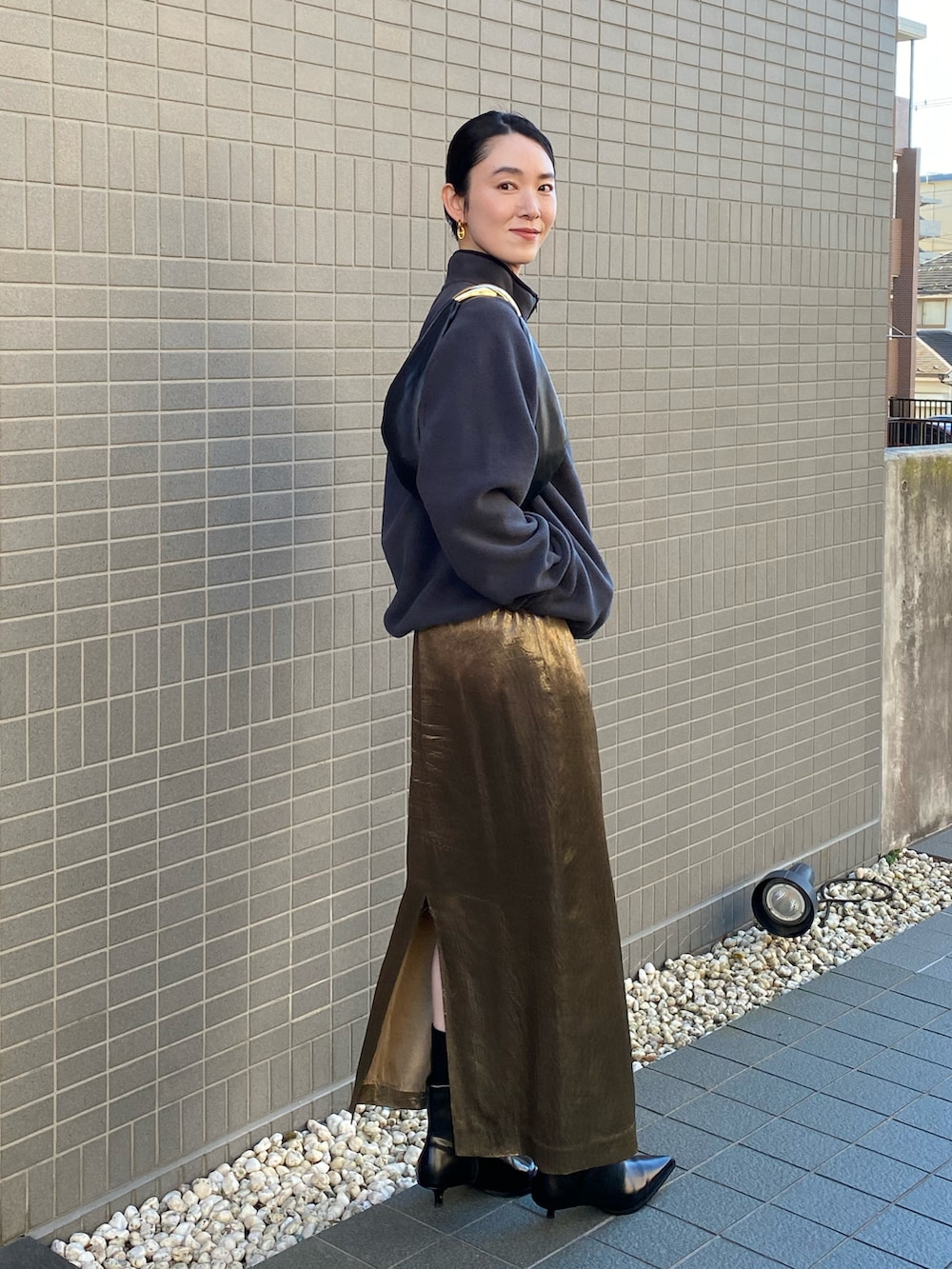 ゴールド系のスカート、ブラック系のハンドバッグ、グレー系のその他トップスを着用したレディースの冬コーディネートの4枚目の写真