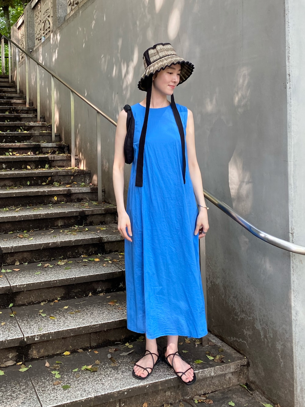 ブルー系のワンピース/ドレス、ブラック系のハンドバッグ、ブラック系のサンダルを着用したレディースの夏コーディネートの2枚目の写真
