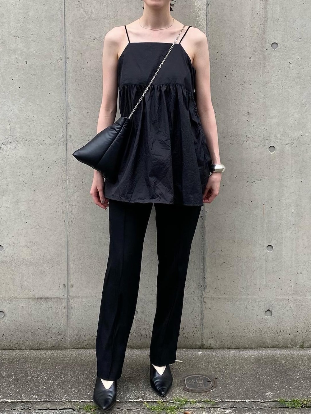 ブラック系のトートバッグ、ブラック系のパンツ、ブラック系のキャミソールを着用したレディースの春コーディネートの4枚目の写真
