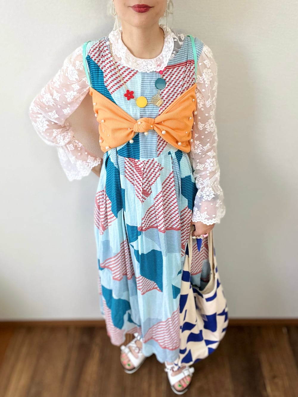 オレンジ系のTシャツ/カットソー、ホワイト系のシャツ/ブラウス、ブルー系のデニムパンツを着用したレディースの夏コーディネートの3枚目の写真