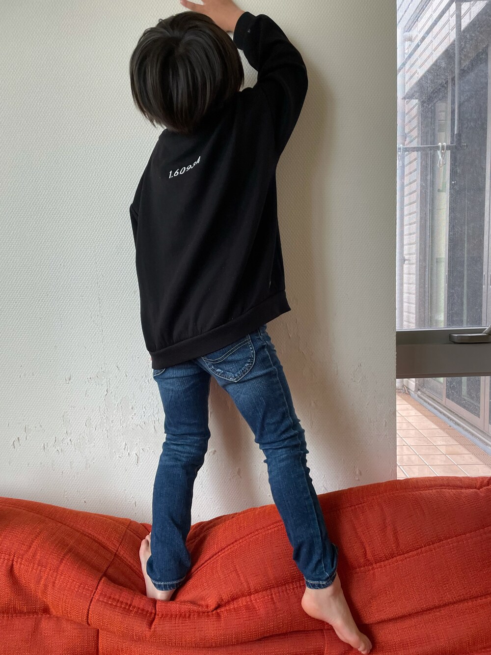 ブラック系のスウェット、ブルー系のデニムパンツを着用したキッズの春コーディネートの2枚目の写真