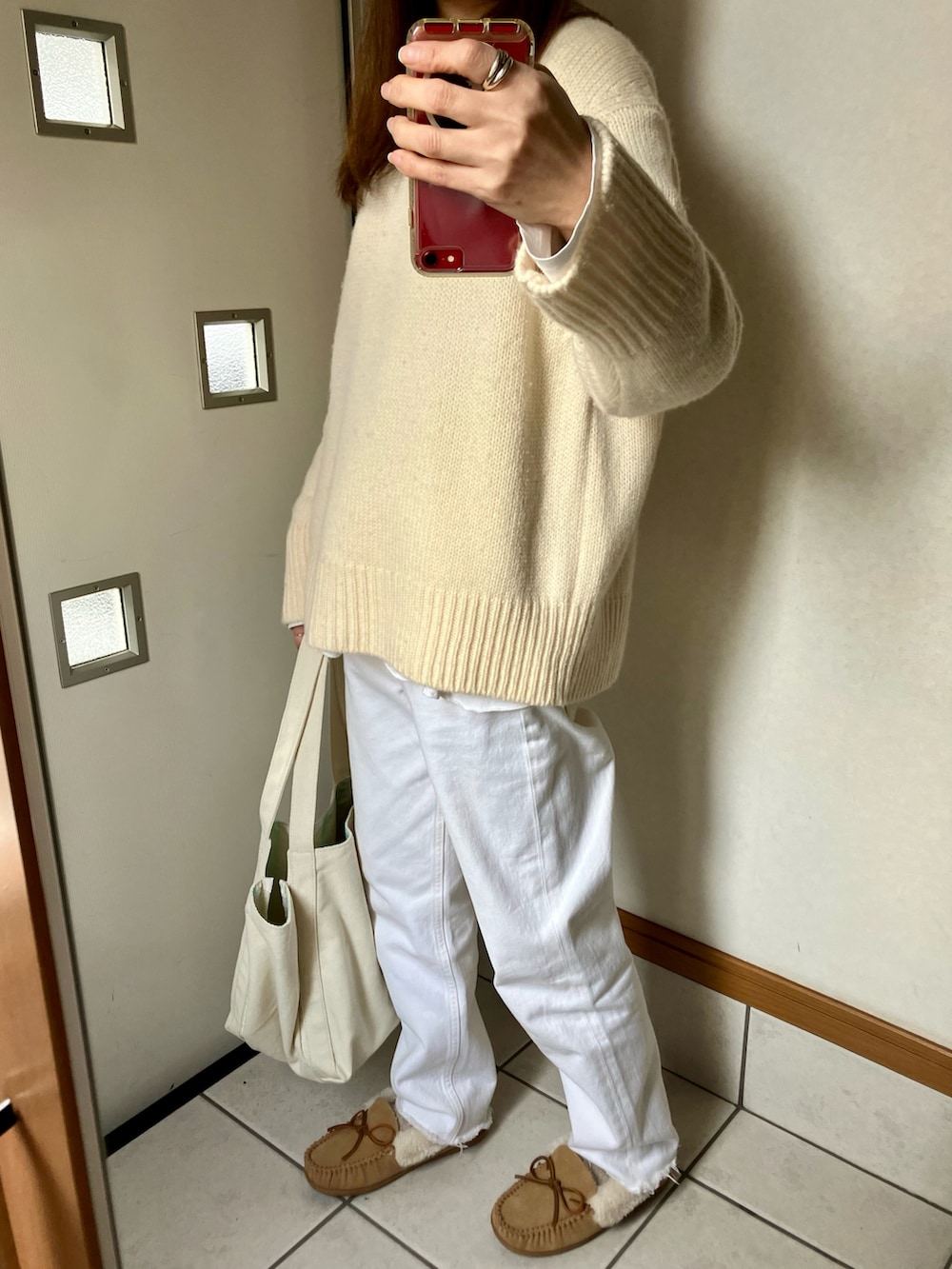 ホワイト系のニット/セーター、ホワイト系のデニムパンツ、ベージュ系のモカシン/デッキシューズを着用したレディースの冬コーディネートの2枚目の写真