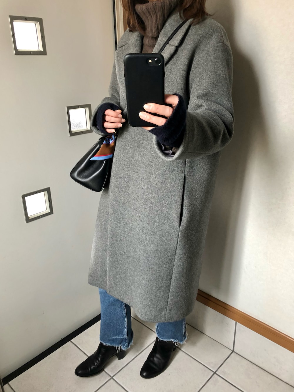 ブラウン系のニット/セーター、ブラック系のブーツ、グレー系のチェスターコートを着用したレディースの冬コーディネートの2枚目の写真