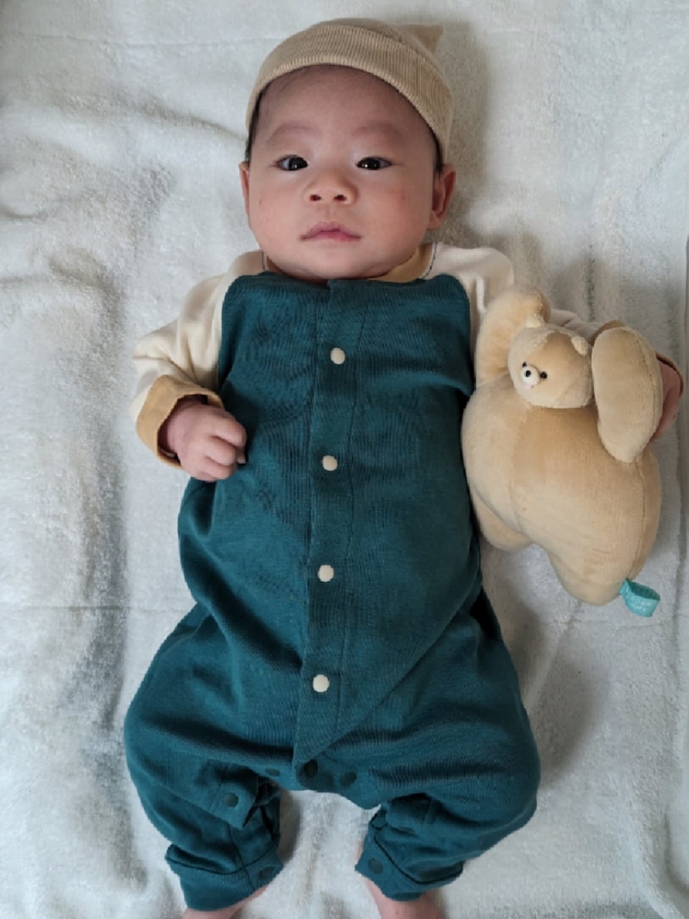 グリーン系のロンパース、ベージュ系の雑貨/ホビー、ベージュ系のその他ベビーウェアを着用したキッズの冬コーディネートの2枚目の写真