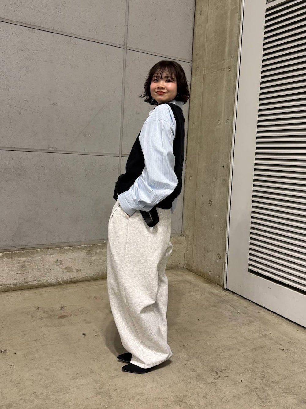 グレー系のスウェットパンツ、ブラック系のパンプス、ブルー系のシャツ/ブラウスを着用したレディースの冬コーディネートの2枚目の写真