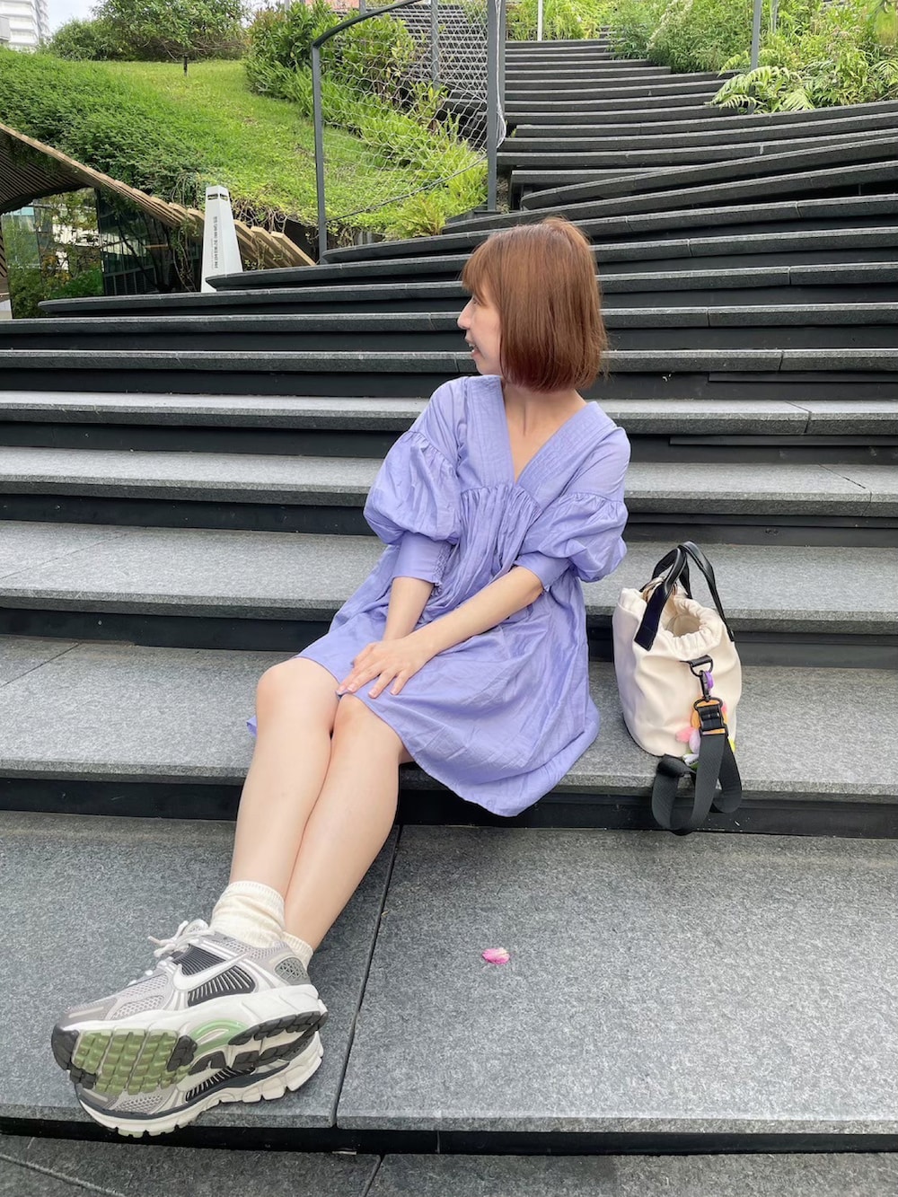 グレー系のスニーカー、ブルー系のワンピース、ホワイト系のショルダーバッグを着用したレディースの秋コーディネートの3枚目の写真