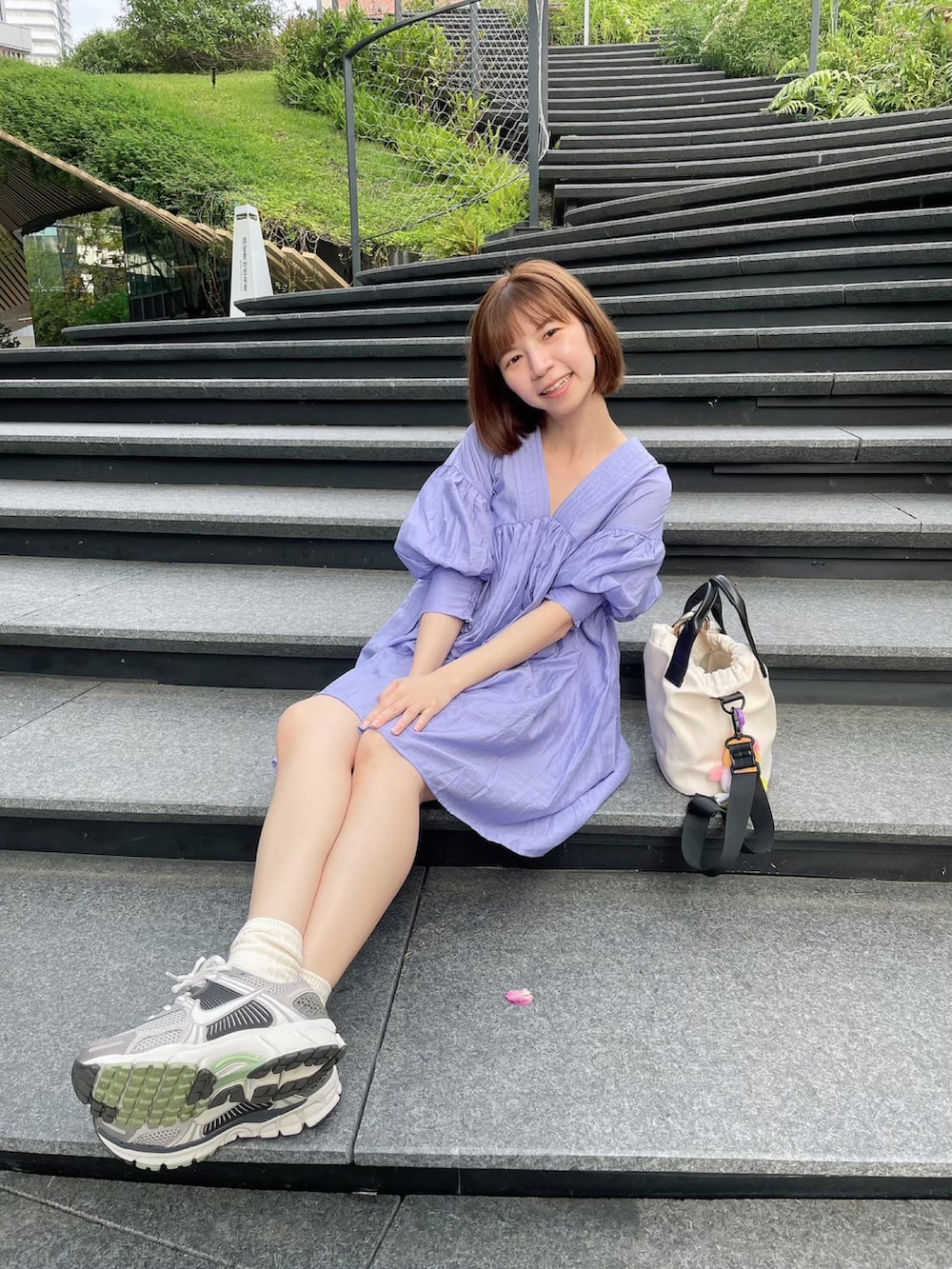 グレー系のスニーカー、ブルー系のワンピース、ホワイト系のショルダーバッグを着用したレディースの秋コーディネートの2枚目の写真