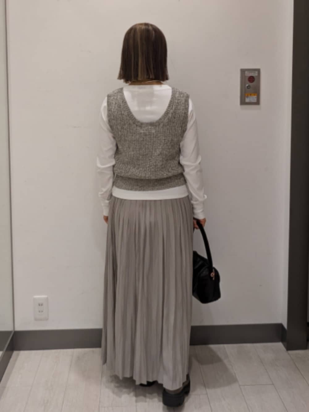 ベージュ系のベスト、ホワイト系のTシャツ/カットソー、ブラック系のトートバッグを着用したレディースの春コーディネートの3枚目の写真