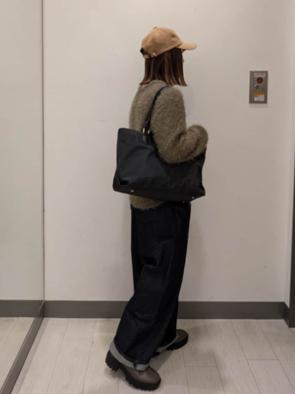 ブルー系のデニムパンツ、グリーン系のニット/セーター、ブラック系のトートバッグを着用したレディースの冬コーディネートの2枚目の写真