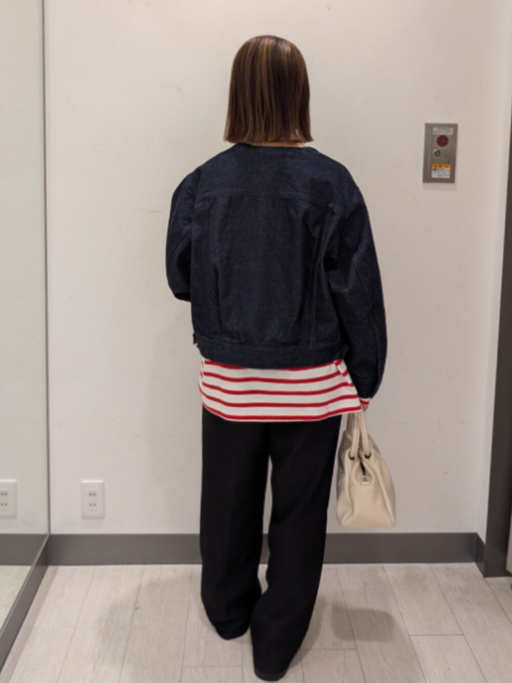 ブルー系のデニムジャケット、ホワイト系のハンドバッグを着用したレディースの冬コーディネートの4枚目の写真