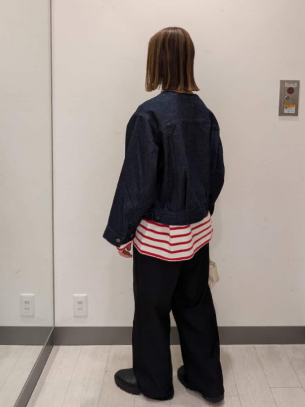 ブルー系のデニムジャケット、ホワイト系のハンドバッグを着用したレディースの冬コーディネートの3枚目の写真