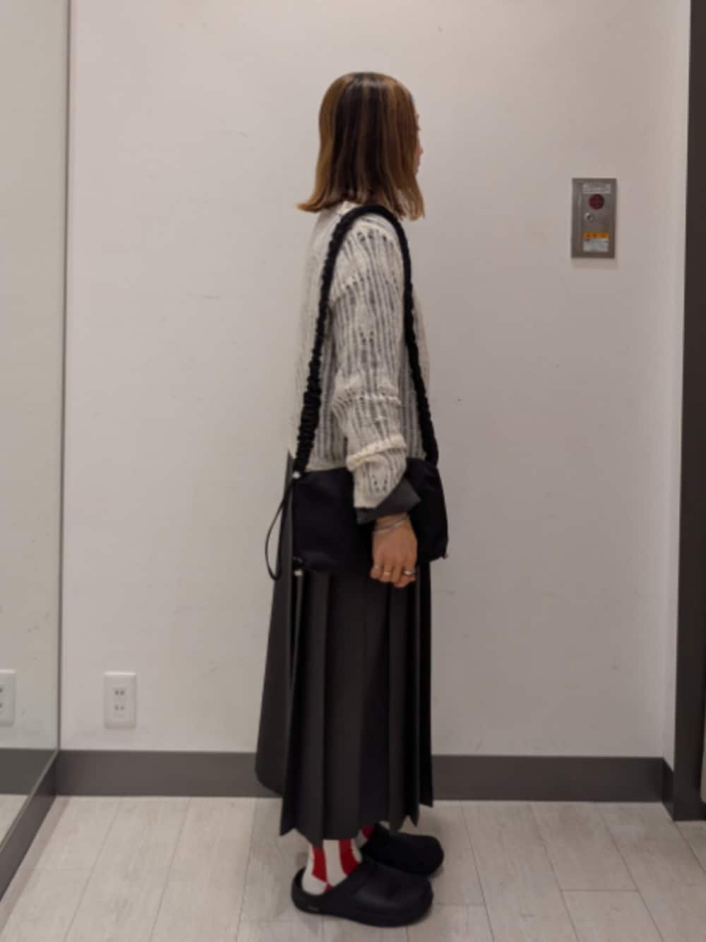 グレー系のワンピース、ブラック系のショルダーバッグ、ホワイト系のカーディガン/ボレロを着用したレディースの秋コーディネートの2枚目の写真