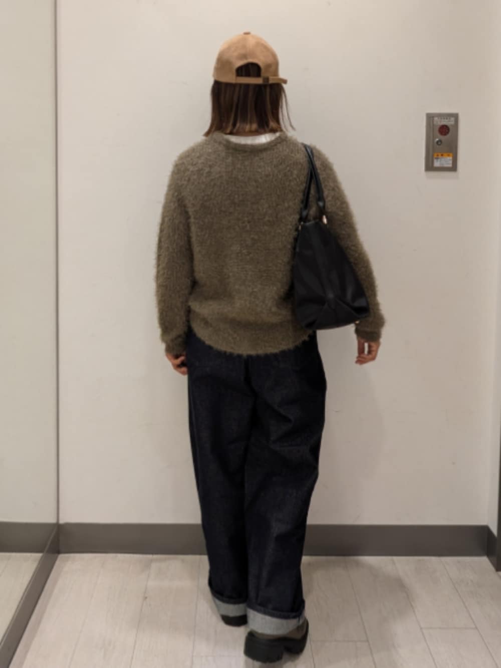 ブルー系のデニムパンツ、グリーン系のニット/セーター、ブラック系のトートバッグを着用したレディースの冬コーディネートの3枚目の写真