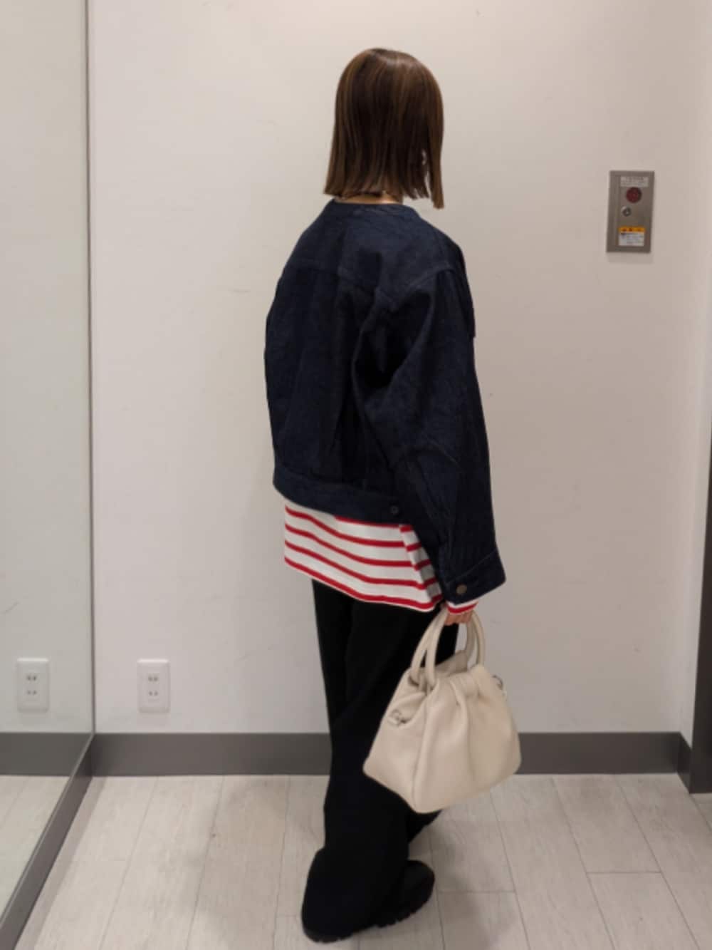 ブルー系のデニムジャケット、ホワイト系のハンドバッグを着用したレディースの冬コーディネートの2枚目の写真