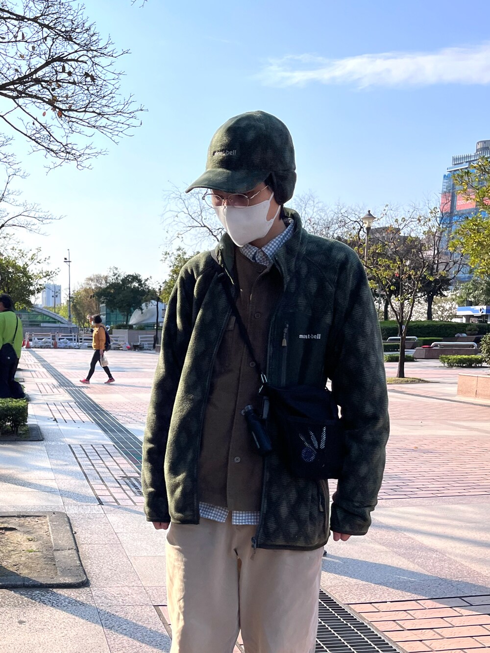 ブラック系のショルダーバッグ、グレー系のスニーカー、ベージュ系のチノパンツを着用したメンズの春コーディネートの2枚目の写真