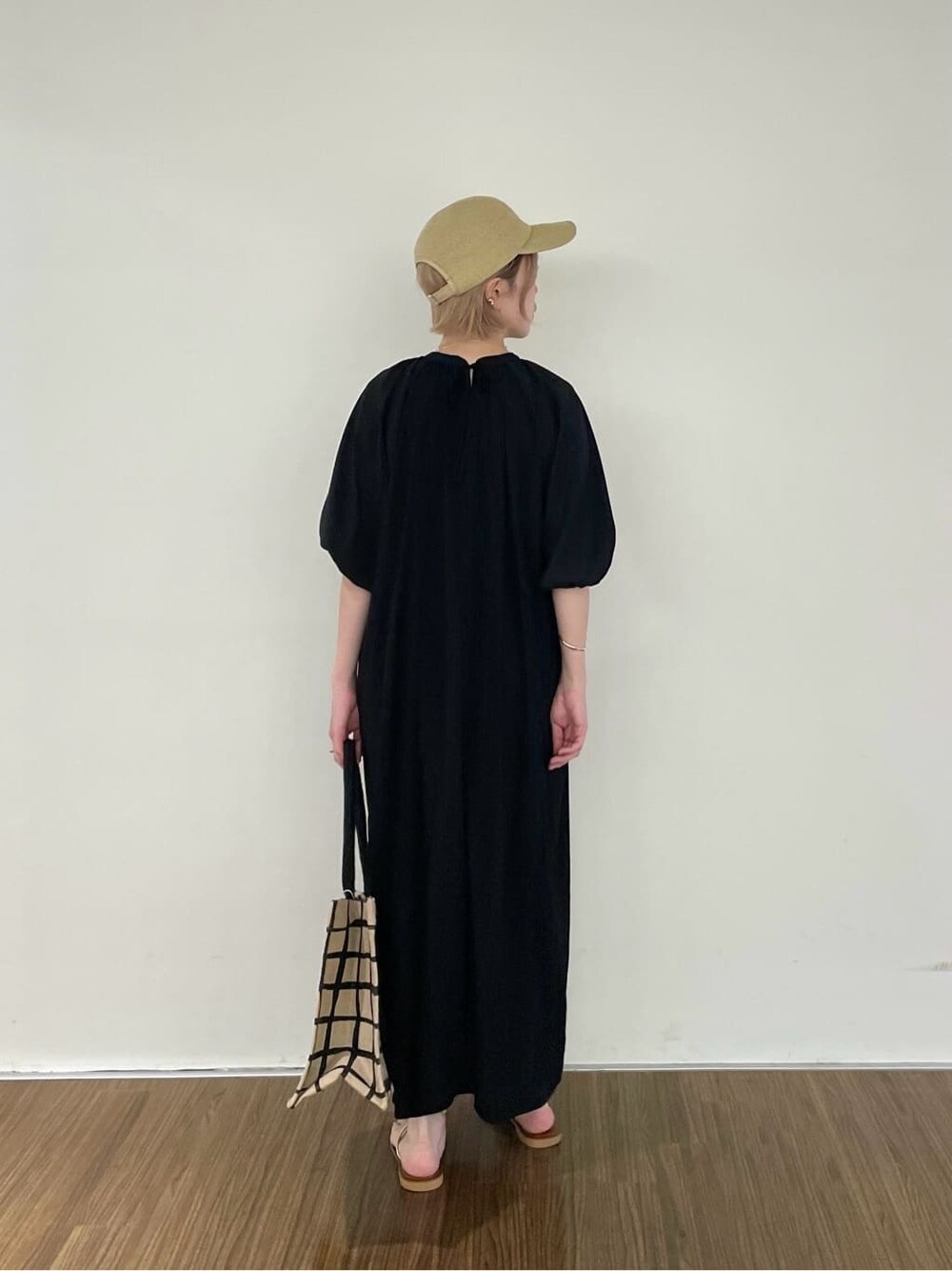 ブラック系のワンピース、ベージュ系のトートバッグ、ゴールド系のリングを着用したレディースの夏コーディネートの5枚目の写真