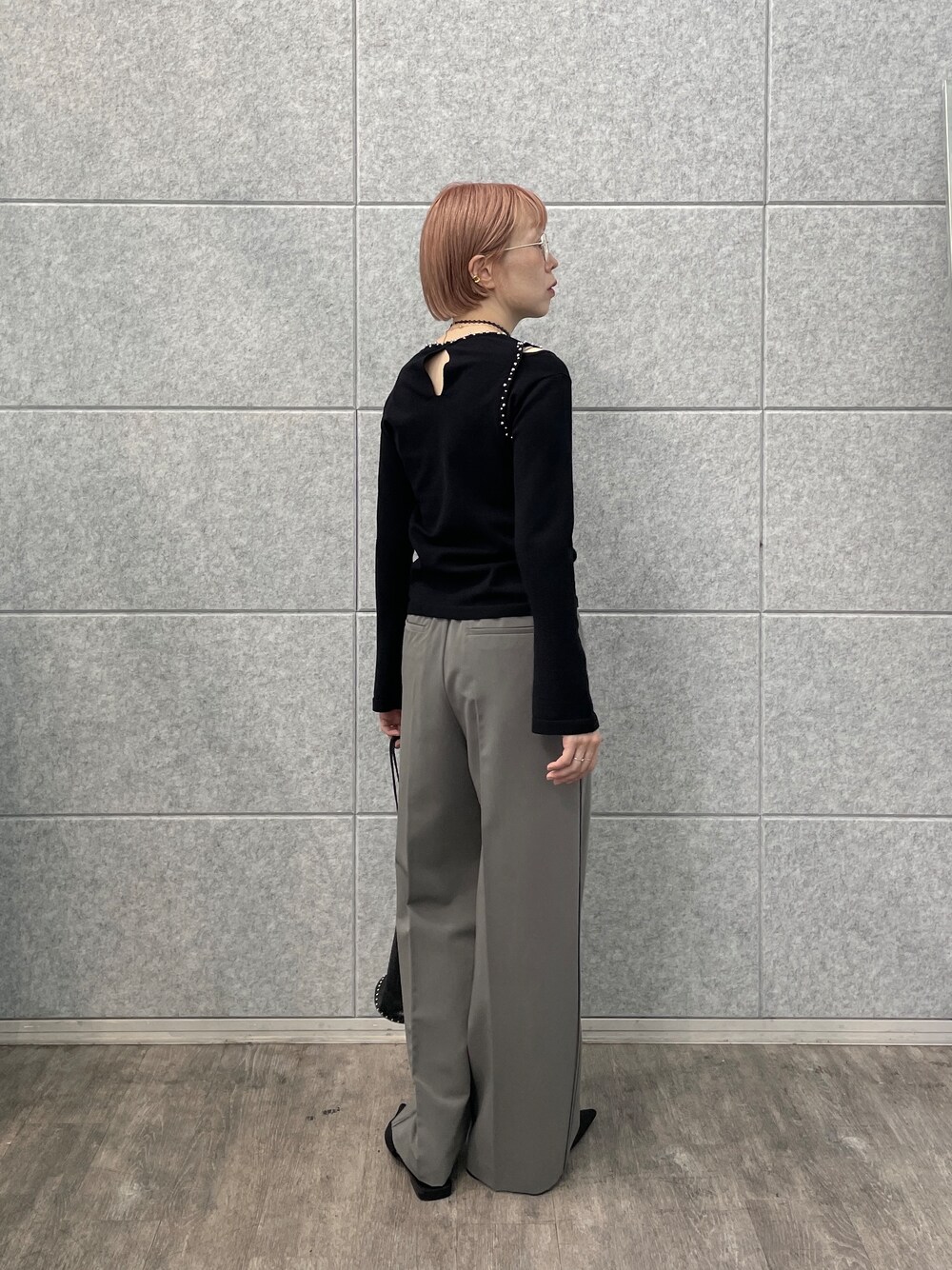 グレー系のその他パンツ、シルバー系のハンドバッグ、ブラック系のニット/セーターを着用したレディースの夏コーディネートの5枚目の写真