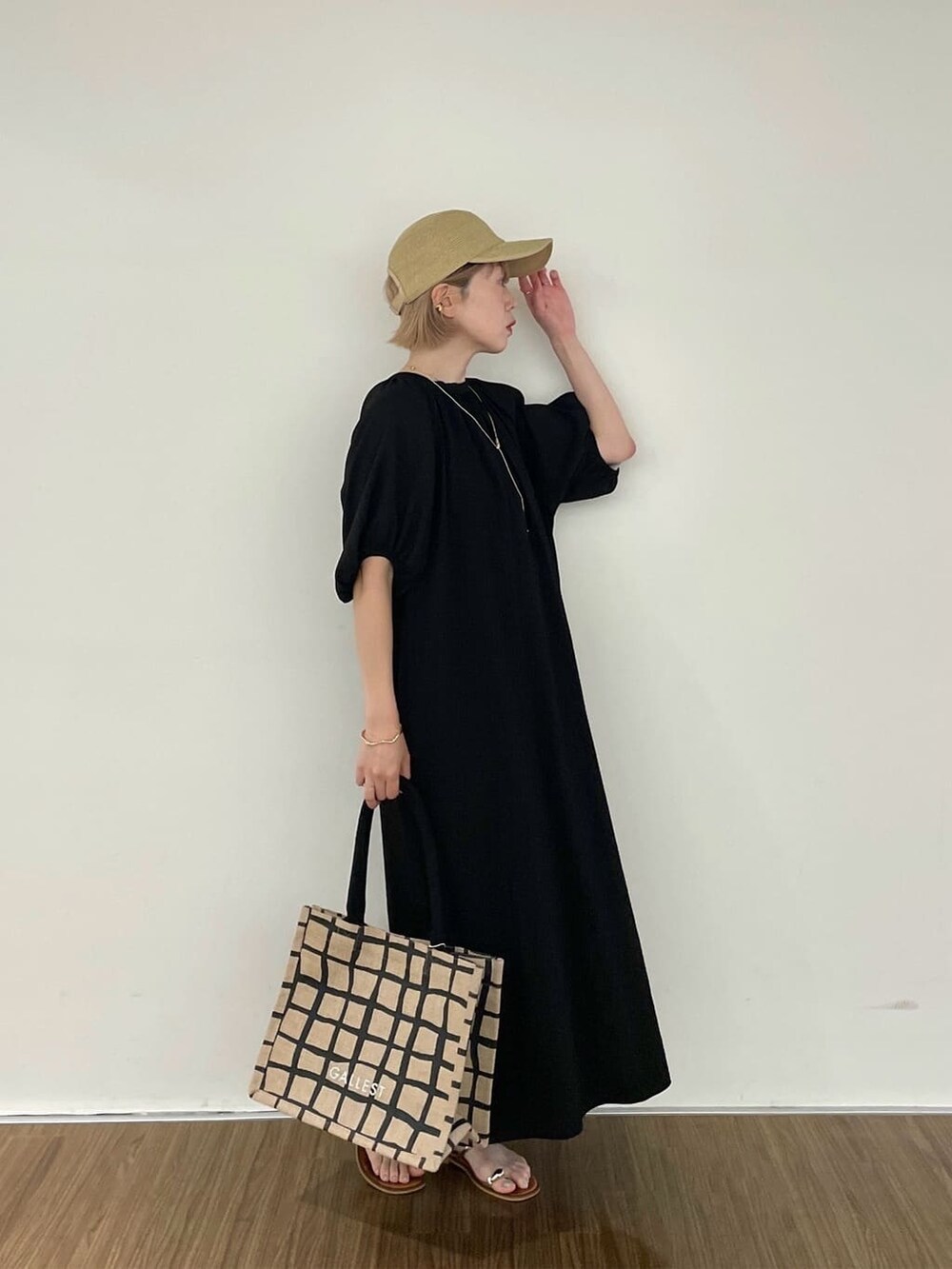ブラック系のワンピース、ベージュ系のトートバッグ、ゴールド系のリングを着用したレディースの夏コーディネートの2枚目の写真