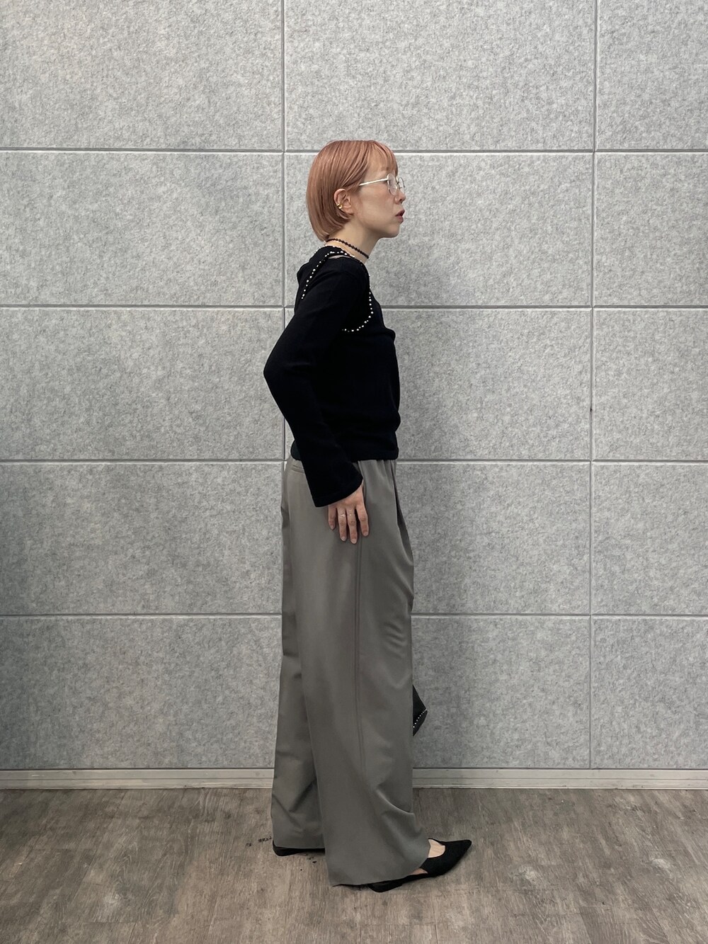 グレー系のその他パンツ、シルバー系のハンドバッグ、ブラック系のニット/セーターを着用したレディースの夏コーディネートの3枚目の写真
