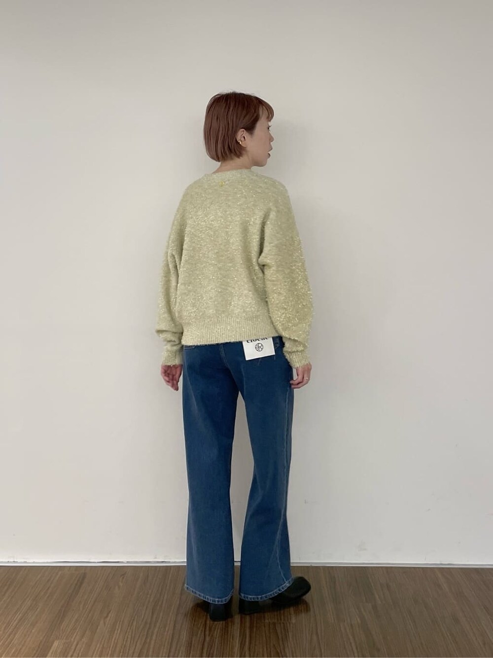 ブルー系のデニムパンツ、ゴールド系のニット/セーターを着用したレディースの秋コーディネートの4枚目の写真