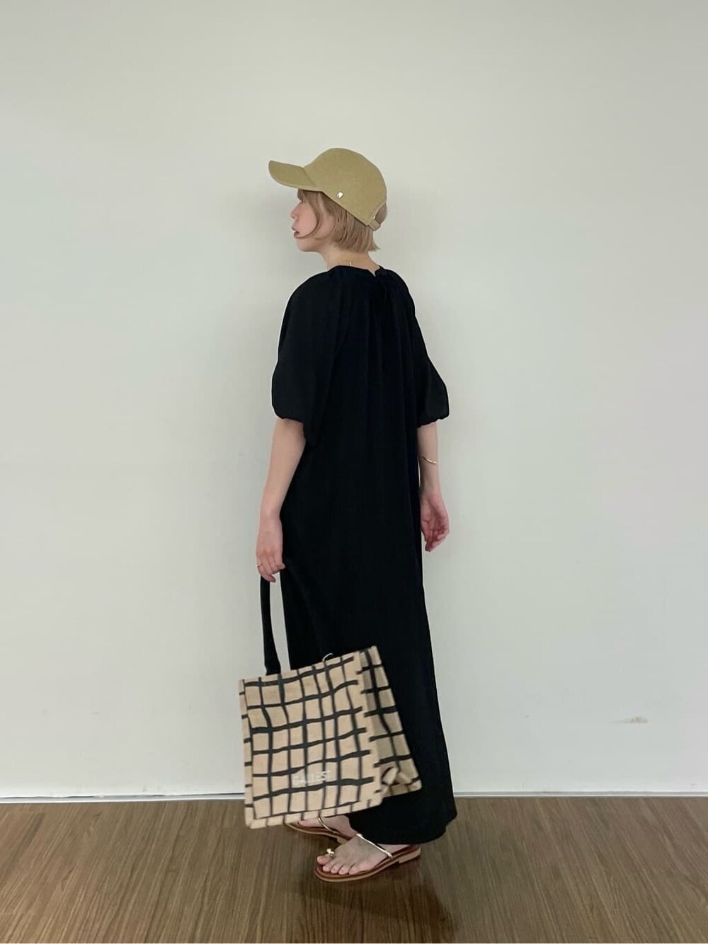 ブラック系のワンピース、ベージュ系のトートバッグ、ゴールド系のリングを着用したレディースの夏コーディネートの4枚目の写真