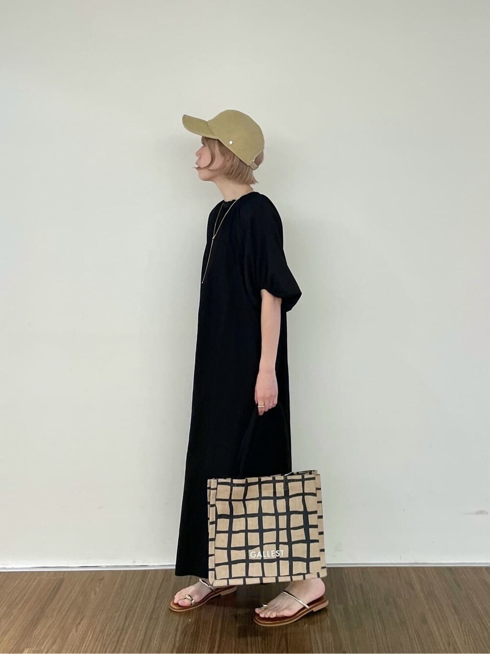 ブラック系のワンピース、ベージュ系のトートバッグ、ゴールド系のリングを着用したレディースの夏コーディネートの3枚目の写真